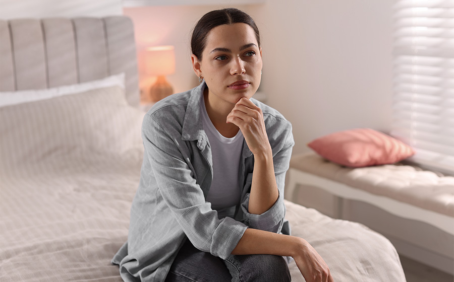 Zmartwiona kobieta siedzi na łóżku doświadczając lęku po transplantacji
